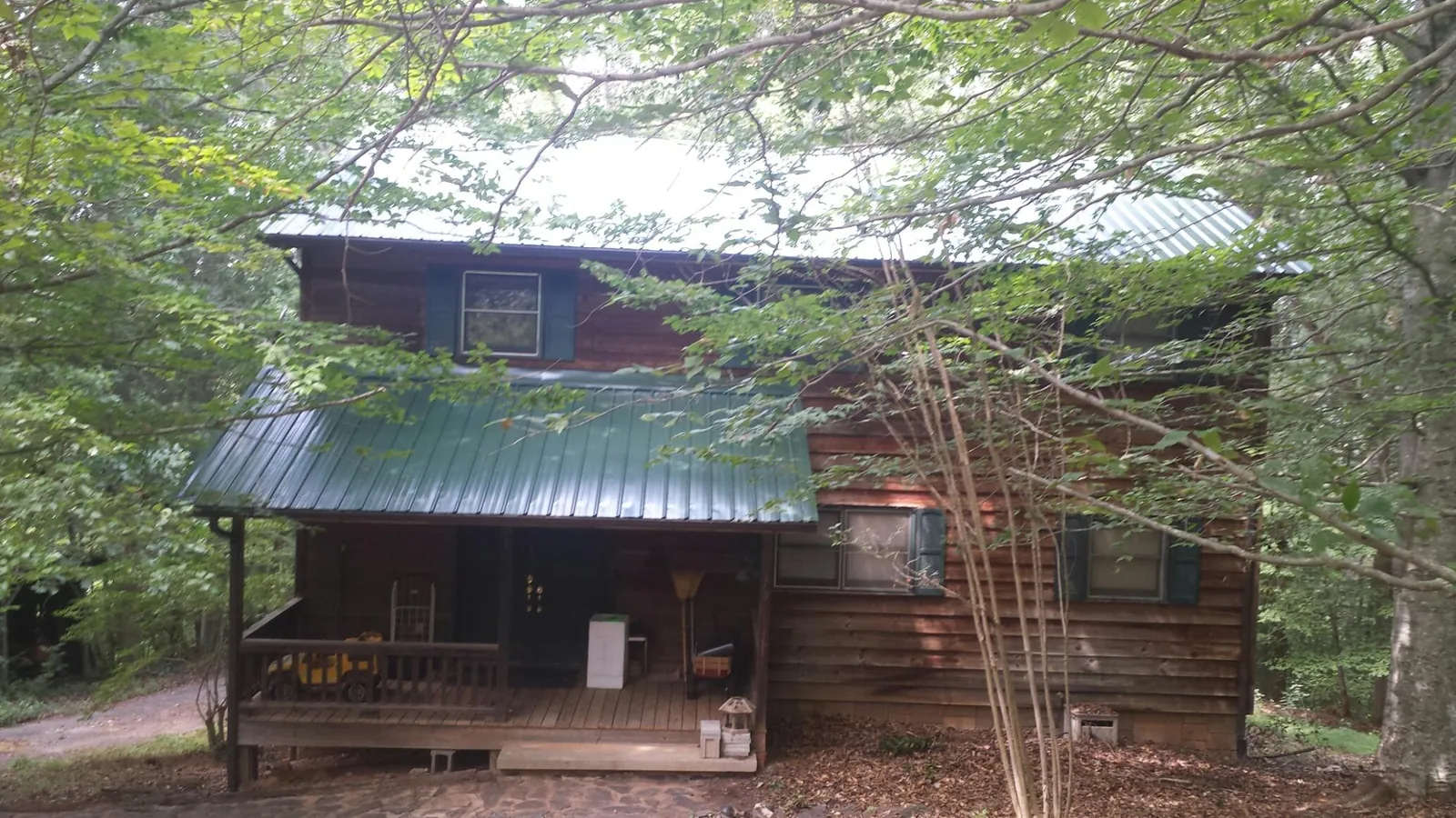 Green metal roof and covered porch on a log cabin in Jacksonville